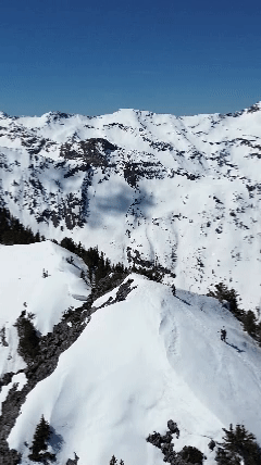 Drone Shot of skiers booting up and summiting a mountain